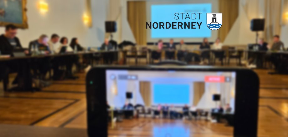 Das Bild zeigt eine Ausschusssitzung mit Blick durch ein Handy