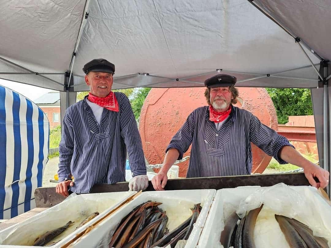 Das Bild zeigt Lionsmitglieder am Räucherfischstand